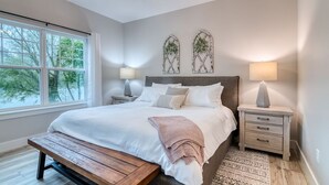 Un dormitorio con una cama grande, mesitas de noche, un banco y un ventilador de techo.