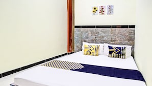 Ein ordentlich bezogenes Bett mit gemusterten Kissen und einer blauen Tagesdecke.
