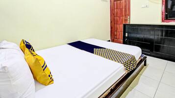 A single bed with a white mattress, a yellow pillow, and a patterned blanket.
