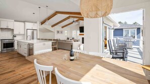 Une cuisine moderne avec des meubles blancs, un îlot central en bois et un coin repas comprenant une table et des chaises.