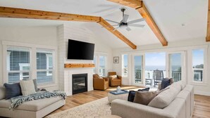 Un salon spacieux doté d’une cheminée, d’un téléviseur à écran plat et d’un balcon offrant une vue agréable.