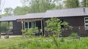 A rustic cabin with a metal roof, wooden deck, and a fenced yard. - Minutes from Pymatuning, Cabin by the Pond (Williamsfield)