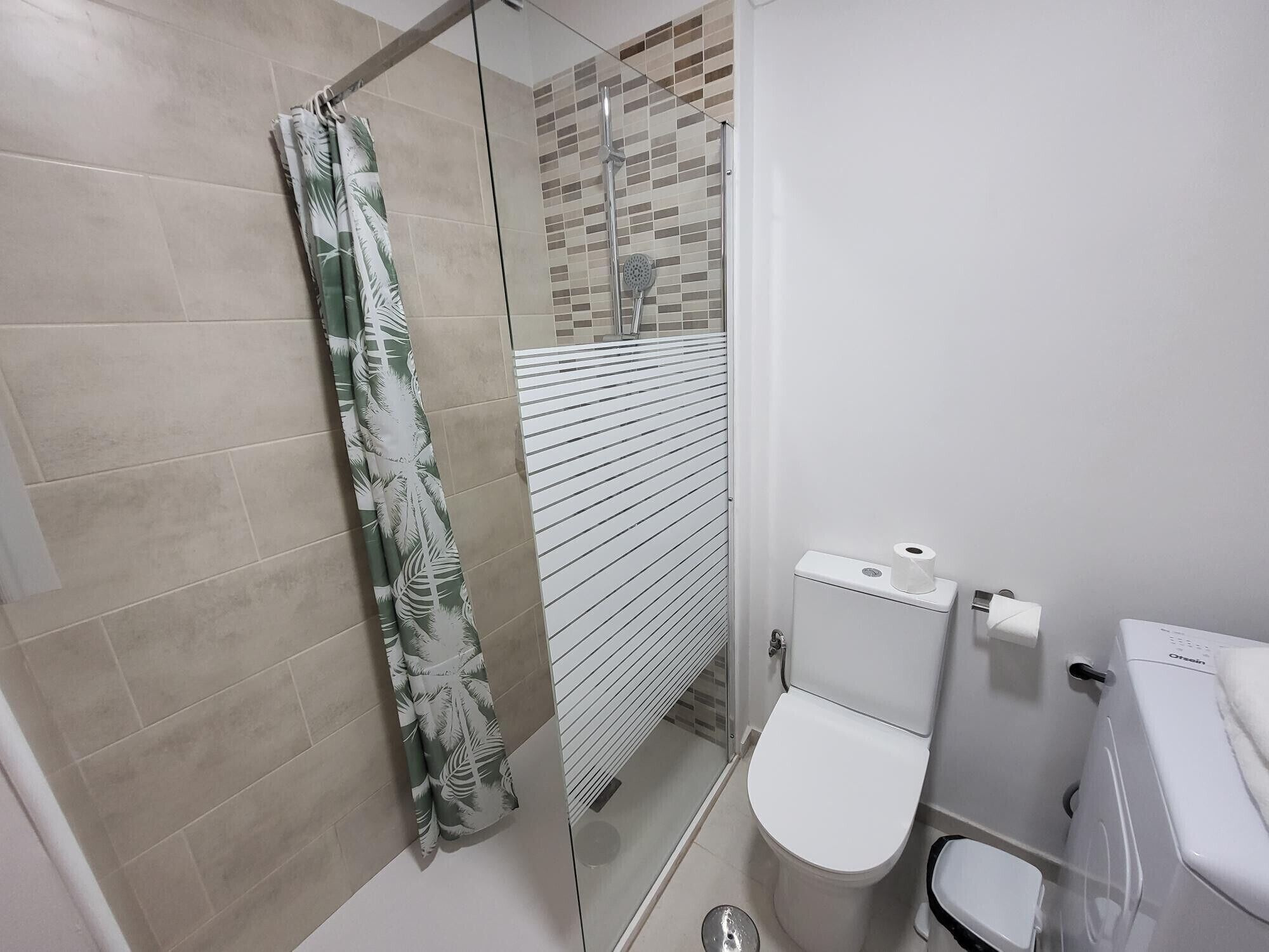 Et badeværelse med brusekabine i glas, toilet og bidet.