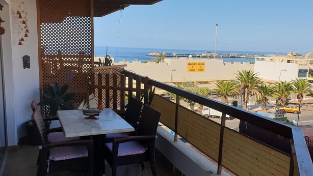 A balcony with a table and chairs, overlooking a marina and beach. - Jardines Canarios 2 (Los Cristianos)