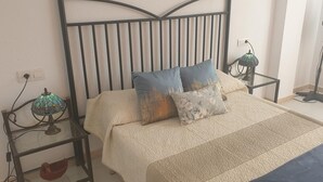 A bed with a headboard, two bedside tables, a lamp, and a floor lamp. - Jardines Canarios 2 (Los Cristianos)