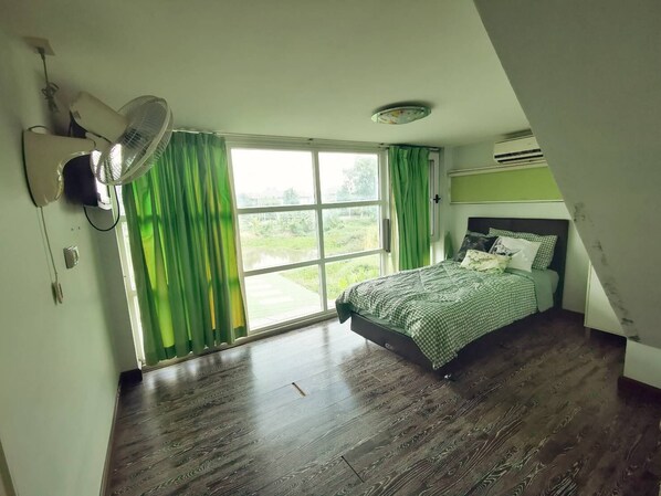 A bedroom with a large window, a bed, and a ceiling fan. - Summer Cottage Apartel (Bangkok)