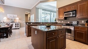 Una cucina moderna con piani in granito, mobili in legno, elettrodomestici in acciaio inossidabile e una grande isola.