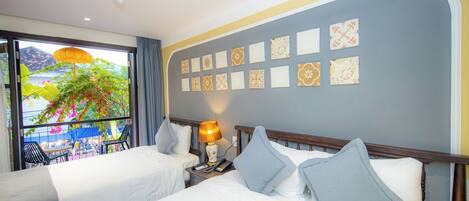 Habitación de hotel con dos camas, balcón con vista a palmeras y pared decorada con baldosas estampadas.