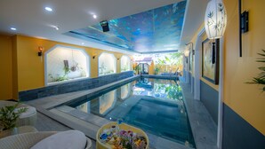 A swimming pool with a ceiling mural, a lounge area with seating, and a view of the outdoors. - Hoianan Boutique Hotel (Da Nang)