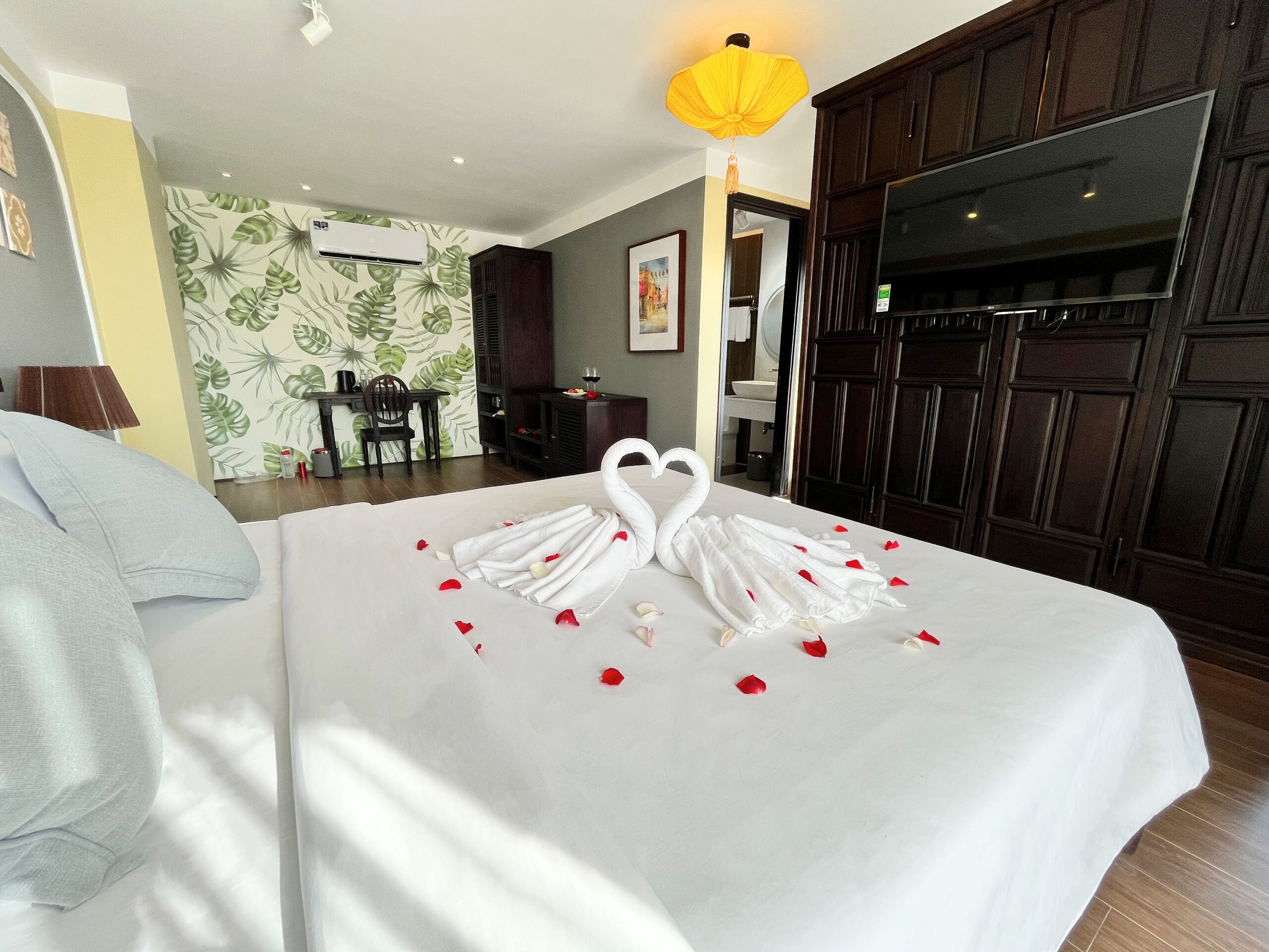 A hotel room with a bed, a desk, a chair, a TV, and a wardrobe.