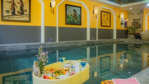 A poolside area with a dining setup featuring a basket of food and drinks, surrounded by artwork on the walls. - Hoianan Boutique Hotel (Da Nang)