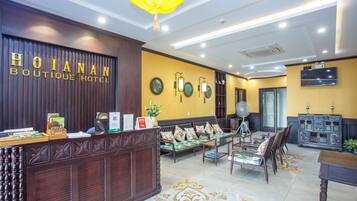 A reception area with a wooden reception desk, a sofa set, and a dining table.