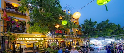 A bustling street scene with a hotel named "Hotel Hoi An Boutique" and a restaurant called "Lamonia Pub."