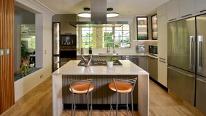 A modern kitchen with a central island, stainless steel appliances, and a view of the outdoors. - Tortuga Bay Villa - Close to the Beach and Golf (Punta Cana)