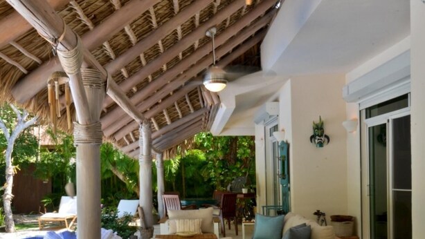 An outdoor dining area with a long table, wicker chairs, and a thatched roof structure. - Tortuga Bay Villa - Close to the Beach and Golf (Punta Cana)