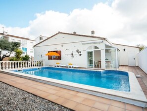 A residential property with a swimming pool, a glass-enclosed patio, and a white exterior.