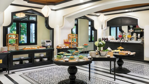 Um saguão de hotel com um serviço de buffet, um espaço para café e uma área de recepção.