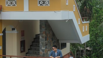 Un edificio de varios pisos con fachada amarilla, escaleras de piedra y un balcón con barandilla.