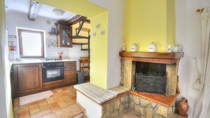 A kitchen with a stone fireplace, wooden cabinets, and a tiled floor. - Casa Binetta A: A characteristic and welcoming two-story independent house situated in the heart of the Tuscan countryside. (Santa Fiora)