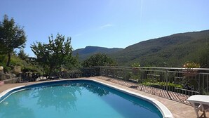 A swimming pool with a curved edge, surrounded by a stone deck and metal railing. - Casa Binetta B: A characteristic and welcoming two-story independent house situated in the heart of the Tuscan countryside. (Santa Fiora)