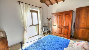 A bedroom with a bed, wooden wardrobe, and a window with curtains. - Casa Binetta B: A characteristic and welcoming two-story independent house situated in the heart of the Tuscan countryside. (Santa Fiora)