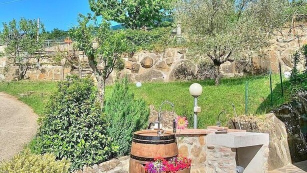 A rustic outdoor setting with a stone wall, a wooden barrel, and a small fountain. - Casa Binetta B: A characteristic and welcoming two-story independent house situated in the heart of the Tuscan countryside. (Santa Fiora)