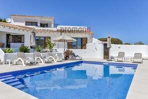 Une villa moderne dotée d’une piscine, de murs blancs et d’un toit recouvert de tuiles.