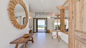 Un pasillo espacioso con un banco de madera, un espejo grande y un perchero. Se ve la palabra 'promana' en la pared.