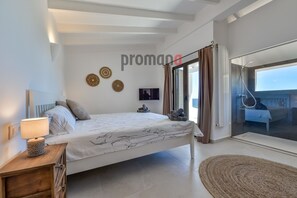 Une chambre moderne avec un grand lit, une table de chevet avec une lampe, une télévision et des œuvres d’art décoratives au mur.