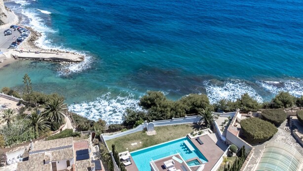Vista aérea de una propiedad costera con piscina, zona de estacionamiento y costa rocosa.