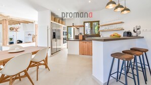 Una cocina moderna con una isla central, armarios de madera y un comedor con mesa y sillas.
