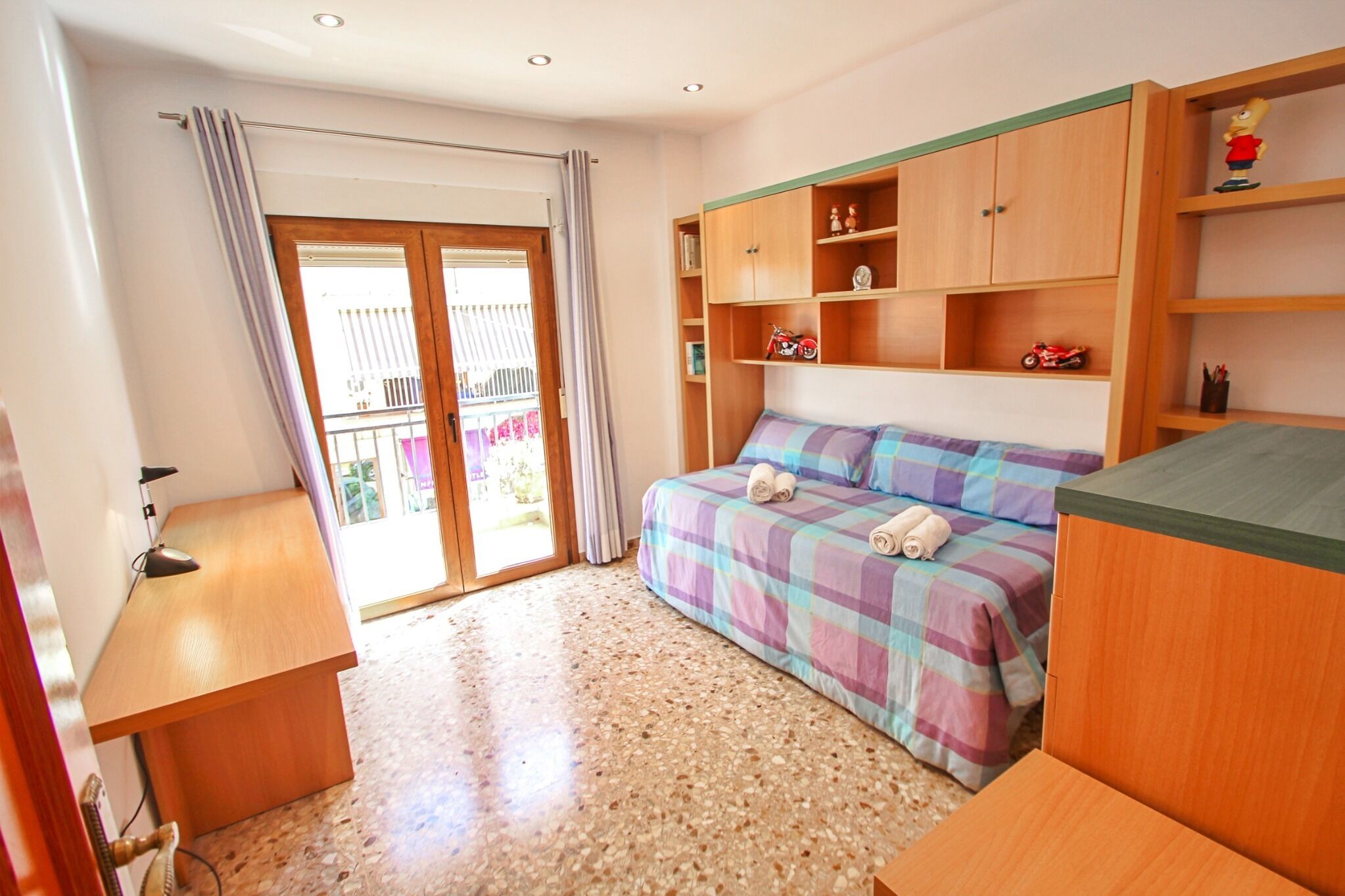 A bedroom with a bed, wooden cabinets, and a desk.