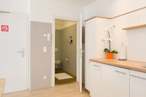 A modern kitchen with white cabinets, a wooden countertop, and a potted orchid.