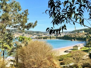 Un paysage côtier avec une plage, un ciel dégagé et une vue sur une ville au loin.