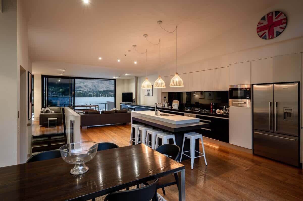 Una cocina moderna con una isla central, electrodomésticos de acero inoxidable e iluminación colgante.