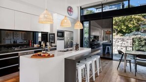 Una cocina moderna con una isla central, iluminación colgante y vistas al exterior.