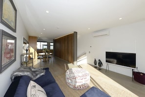 Relax in this stylish living room with a large flat-screen TV, comfortable sofa, and patterned ottoman.