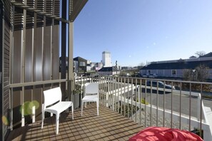 Enjoy the city view from this balcony with a tiled floor, two chairs, and a unique decorative piece.