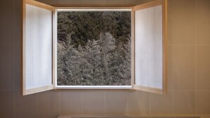 A bathroom with a window overlooking a forested area. - HOTEL YUSURIM (Changwon)