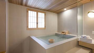 Une salle de bain moderne avec une baignoire sur pieds, un meuble-lavabo en bois et un grand miroir.