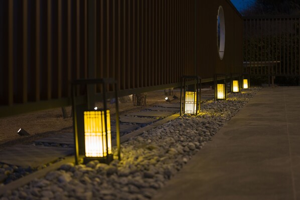 Un sendero bordeado por faroles iluminados que conduce a un edificio con fachada de madera.