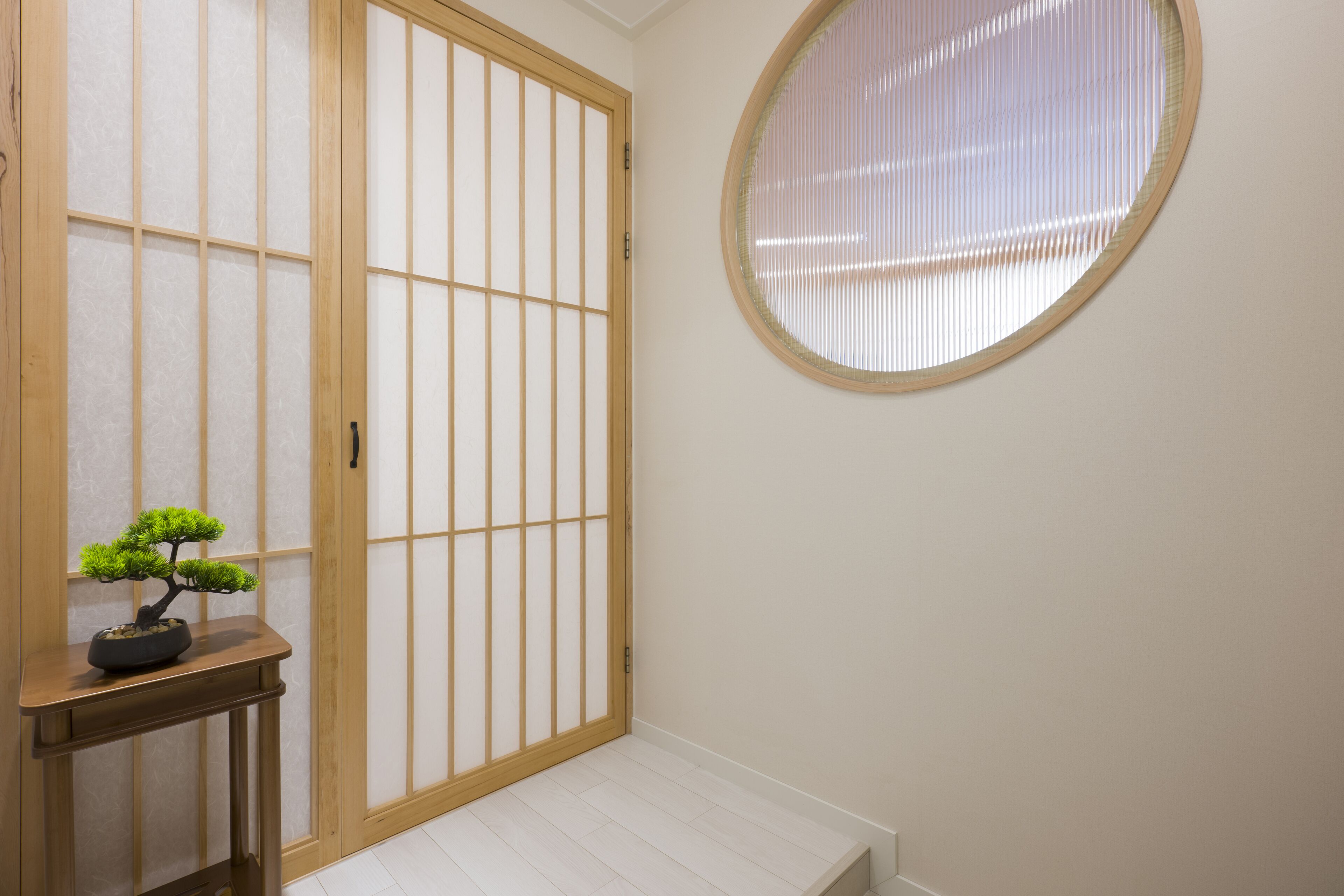 Um quarto japonês tradicional com piso de tatame, porta de shoji e um espelho redondo na parede.