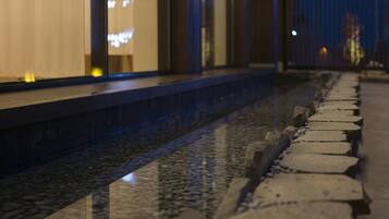 A nighttime view of a stone pathway leading to a building with illuminated windows.