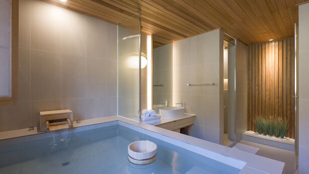 A modern bathroom with a large bathtub, a wooden ceiling, and a small sink area. - HOTEL YUSURIM (Changwon)