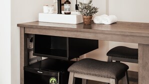 Een moderne badkamer met een wastafel, spiegel, handdoek en een kleine koelkast.