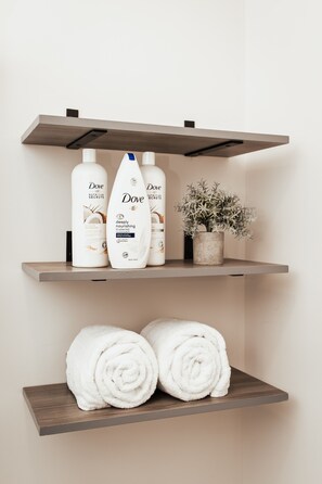 Een plank met Dove verzorgingsproducten, een potplant en opgerolde handdoeken.