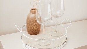 Een witte tafel met een houten vaas en twee glazen wijnglazen op een witte dienblad.