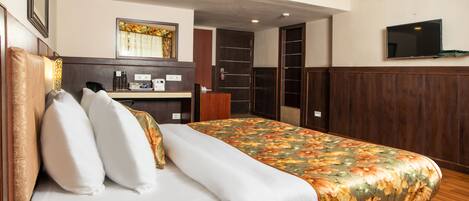 A hotel room with a bed, a desk, a mirror, a wardrobe, and a TV.