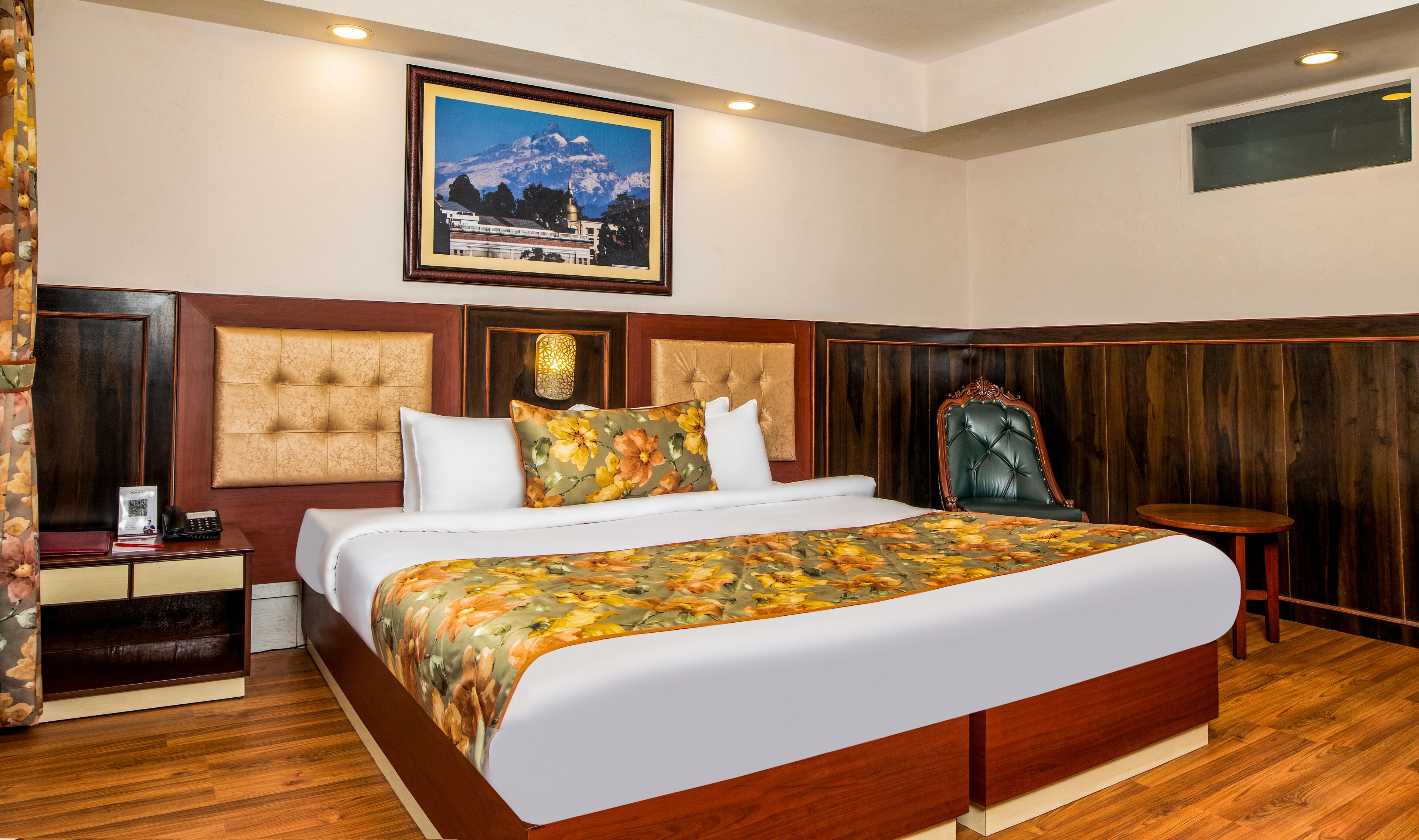 Ein Hotelzimmer mit einem großen Bett, einem Holzkopfstück, einem kleinen Tisch und einem gerahmten Bild an der Wand.