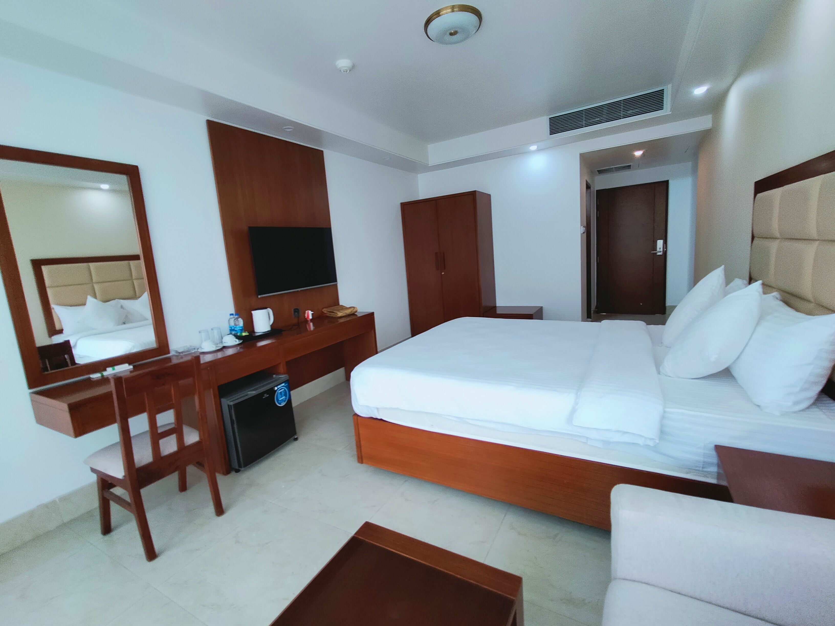 Une chambre d’hôtel avec un grand lit, un bureau, une chaise, une télévision et une armoire.